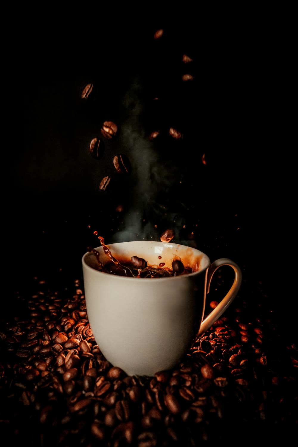 Roasted coffee beans falling into a steaming white cup